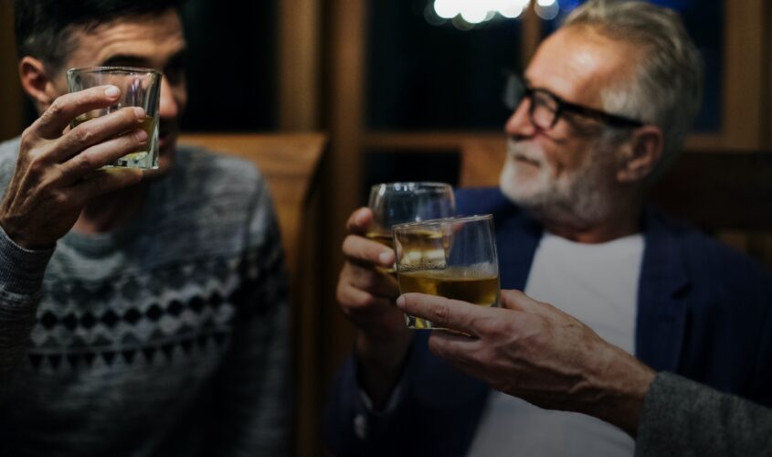 Men in a bar toasting with whiskey glasses