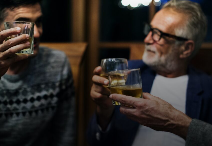 Men in a bar toasting with whiskey glasses