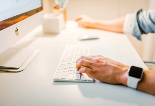 person with apple watch working on mac desktop