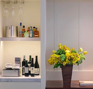 Room with flowers on a nightstand and items on the shelf